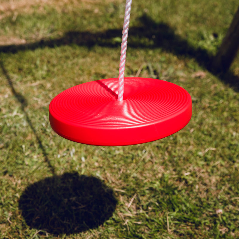 Den røde tallerkengynge fra Nordic Play hænger på et gyngestativ 