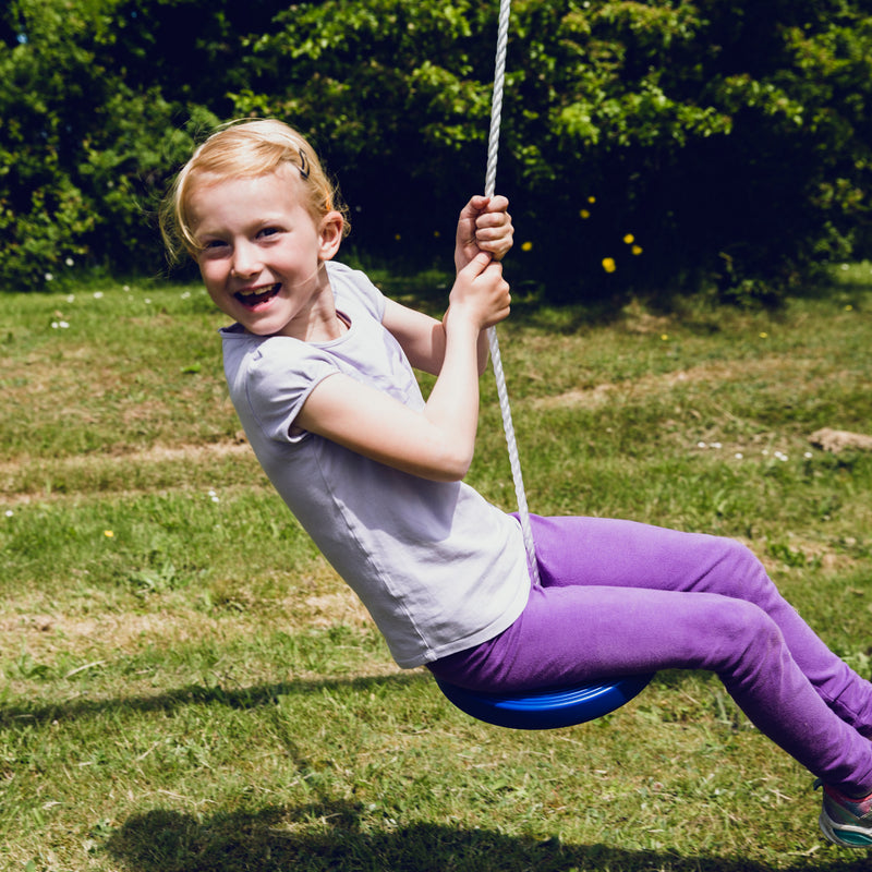 En pige der har sjov på den blå tallerkengynge fra Nordic Play med et hvidt reb 