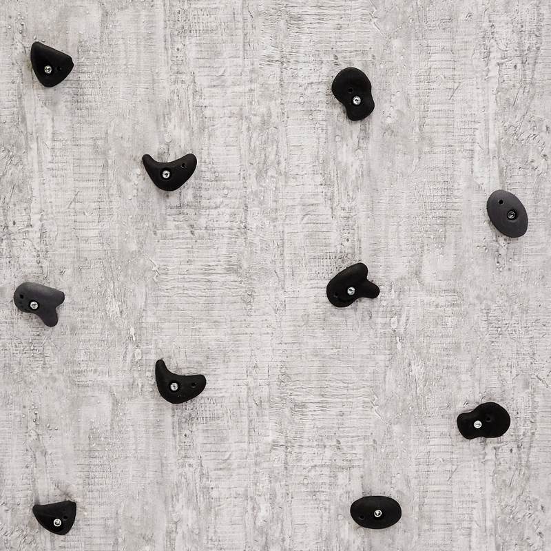 De neutrale klatresten i mørke farver fra  Nordic Play der hænger på en væg 